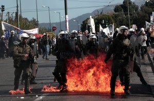 Greek police stand guard amid molotov cocktails thrown by protesters during a massive demonstration as part of a 24-hour general strike in Athens on November 12, 2015. Around 20,000 people demonstrated against fresh cuts in Athens, with sporadic outbreaks of violence, in the first general strike against the leftist government of Alexis Tspiras who swept to power on an anti-austerity ticket. AFP PHOTO / ANGELOS TZORTZINIS        (Photo credit should read ANGELOS TZORTZINIS/AFP/Getty Images)