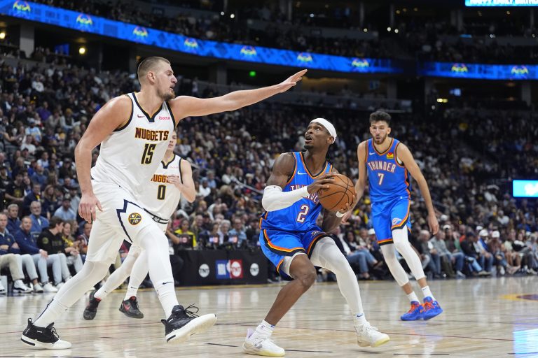 Denver Nuggets center Nikola Jokic, left, blocks Oklahoma City Thunder guard Shai Gilgeous-Alexander as he drives the lane in the second half of an NBA basketball game Thursday, Oct. 24, 2024, in Denver. (AP Photo/David Zalubowski)