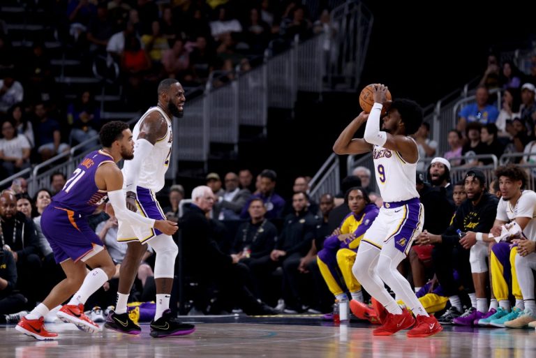 PALM SPRINGS, CALIFORNIA - OCTOBER 06: Bronny James #9 of the Los Angeles Lakers shoots against Tyus Jones #21 of the Phoenix Suns as teammate LeBron James #23 looks on during the second quarter at Acrisure Arena on October 06, 2024 in Palm Springs, California. NOTE TO USER: User expressly acknowledges and agrees that, by downloading and/or using this photograph, user is consenting to the terms and conditions of the Getty Images License Agreement.   Katelyn Mulcahy/Getty Images/AFP (Photo by Katelyn Mulcahy / GETTY IMAGES NORTH AMERICA / Getty Images via AFP)